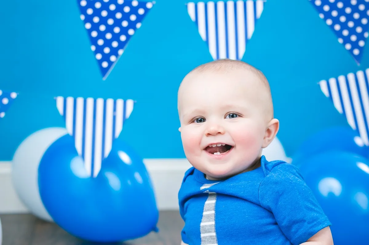 Joyful baby with a light blue smash cake during a fun cake smash photo session
