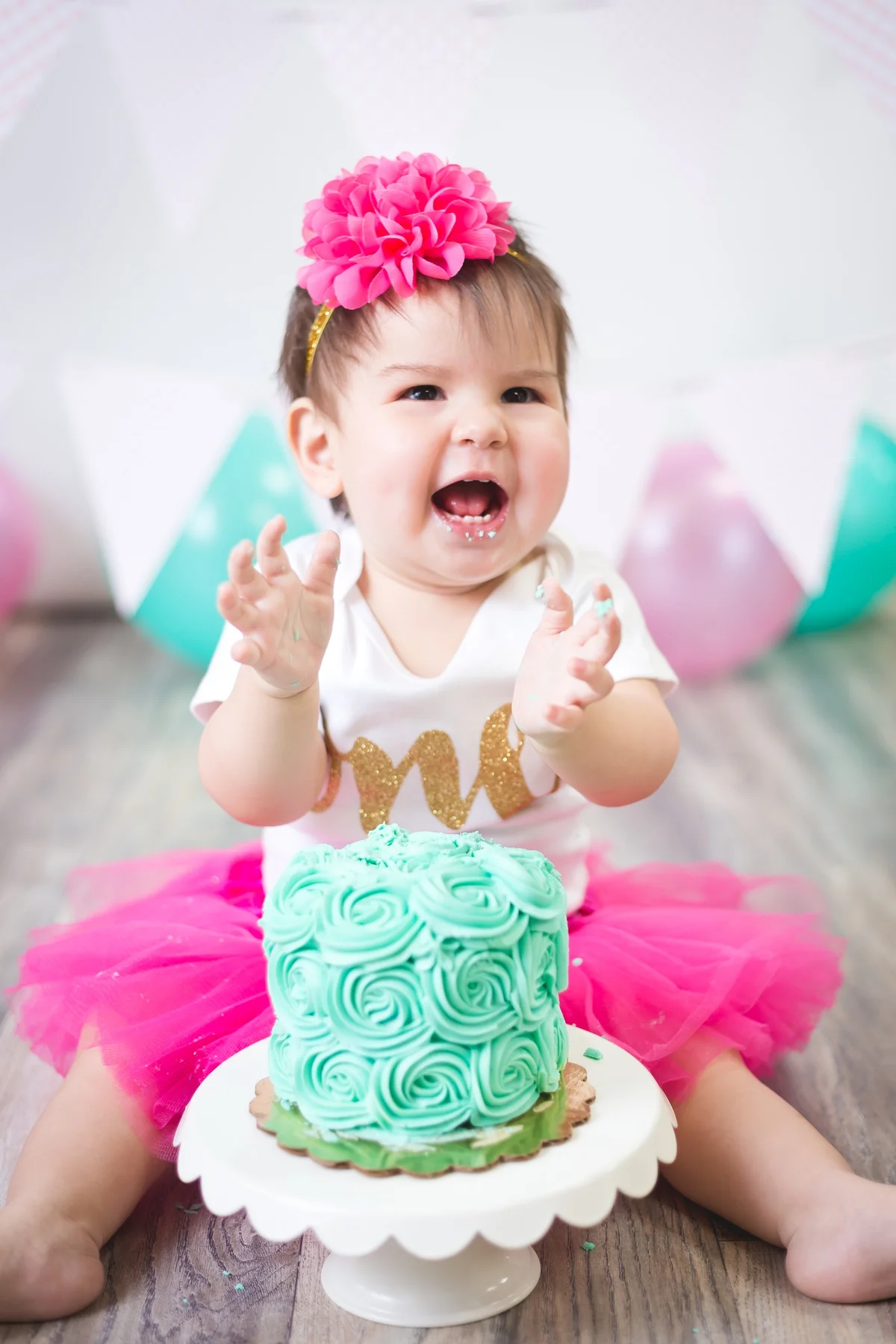 Baby with a beautifully colored teal smash cake during a cake smash photography session in Austin