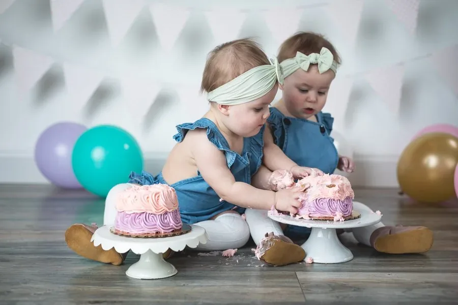 Baby smashing into a yellow-frosted cake with joyful expression during an Austin cake smash photo session