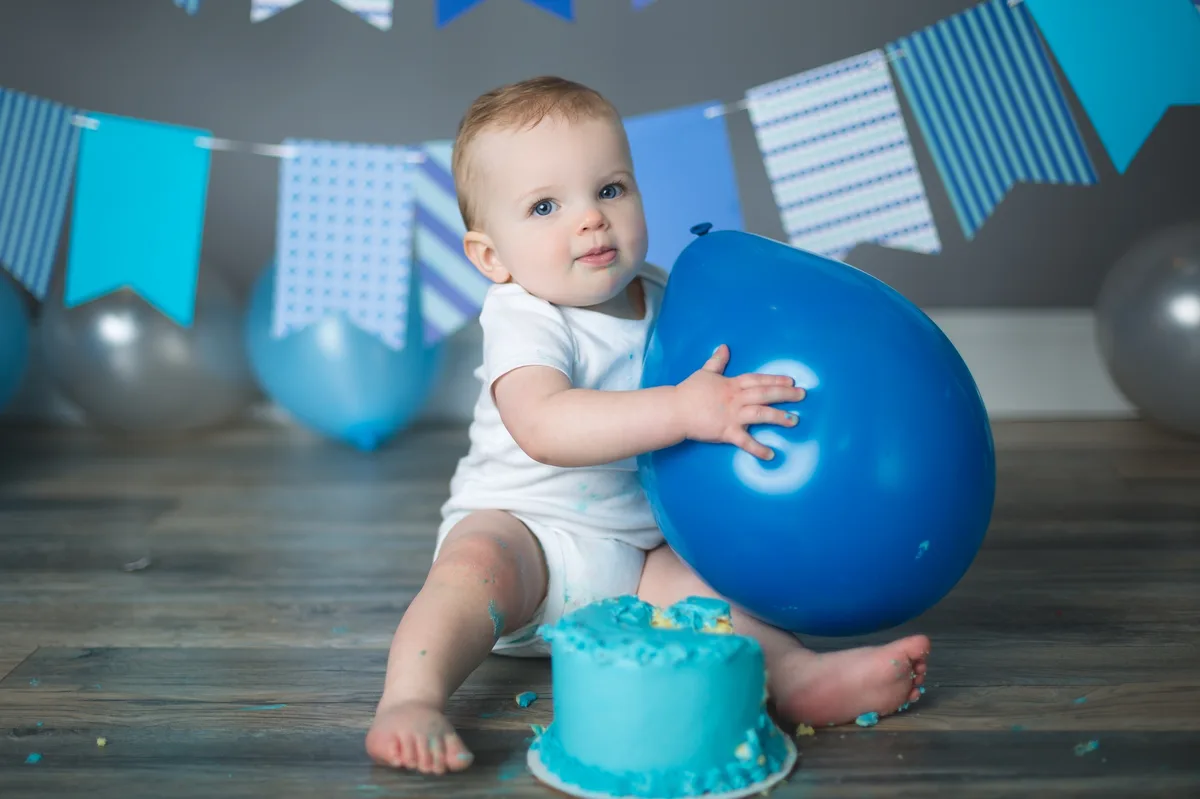Blue cake smash session with coordinated balloons and birthday banner at a Chicago photography studio