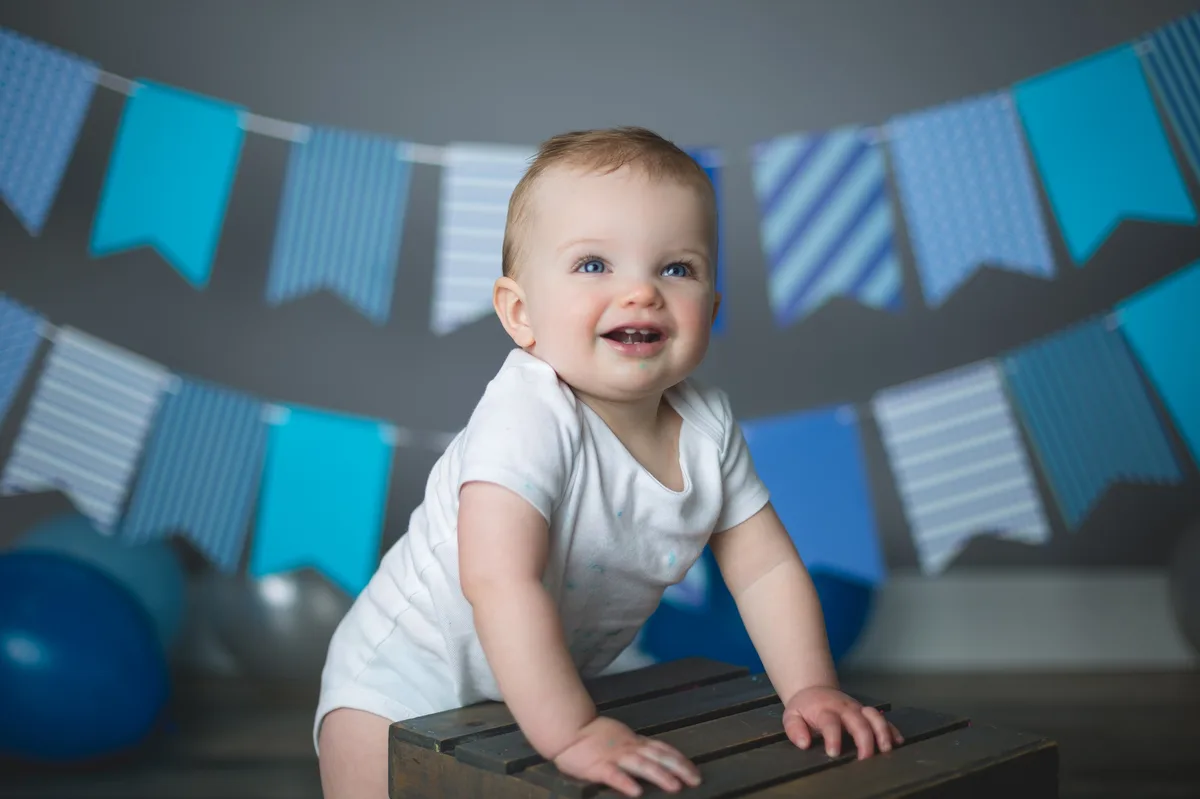 Baby playing with blue frosting during a first birthday cake smash photo session in Chicago
