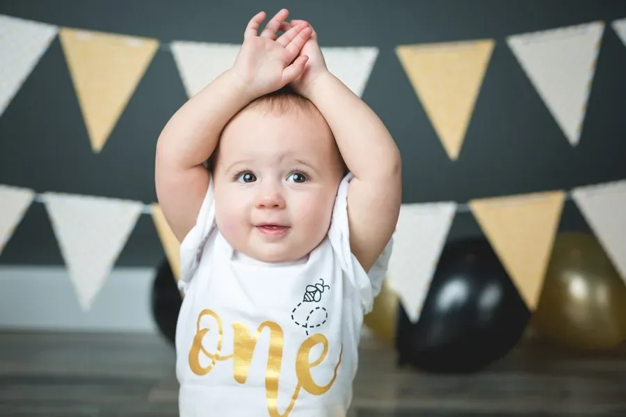 Baby with a pink smash cake, crown, and balloons in a styled studio