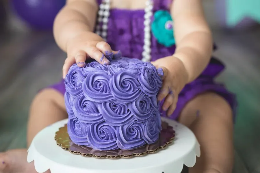 Baby wearing a flower crown during cake smash session with colorful banner backdrop