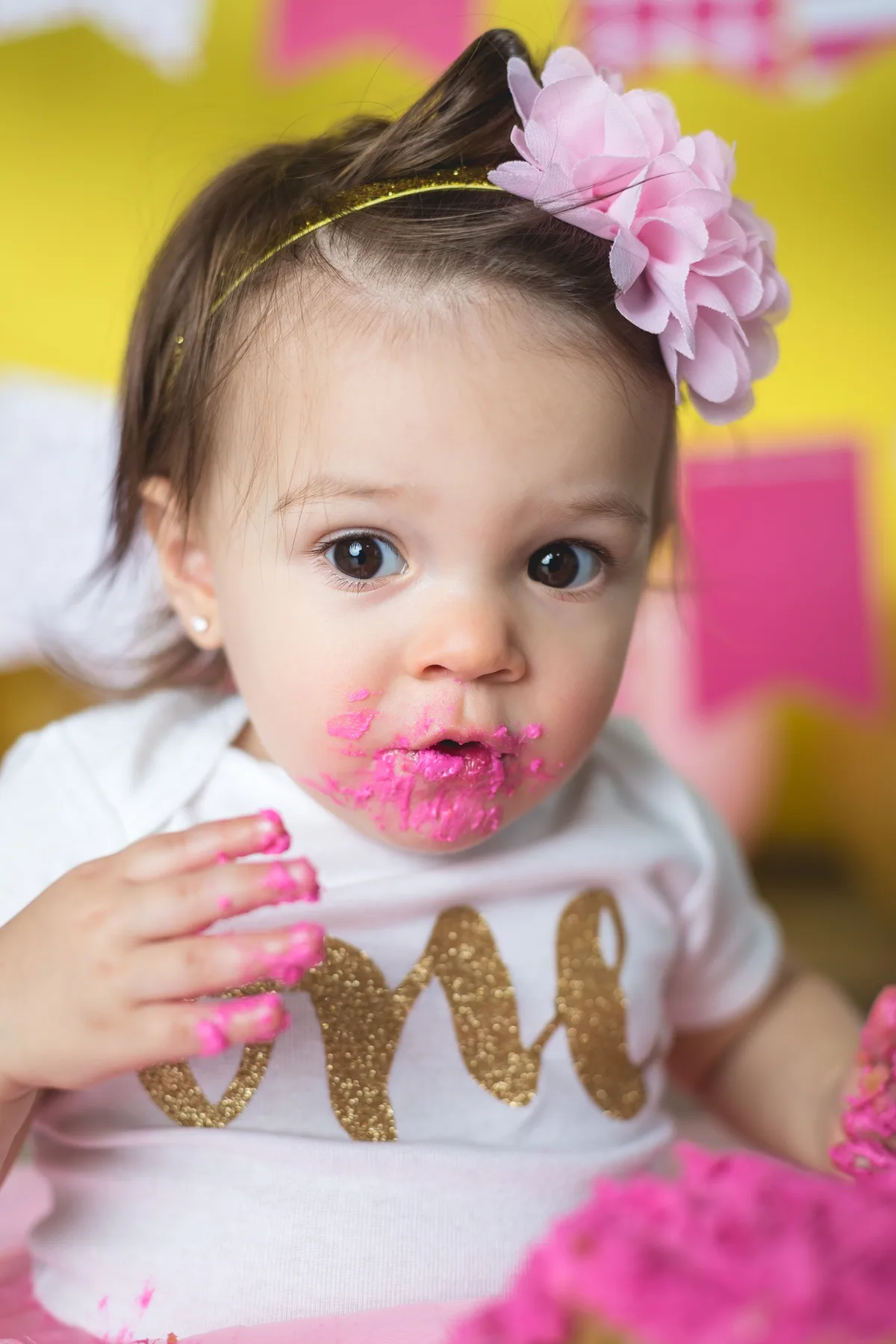 Baby in a hot pink tutu with coordinated cake smash setup and birthday decorations at a Chicago photography studio