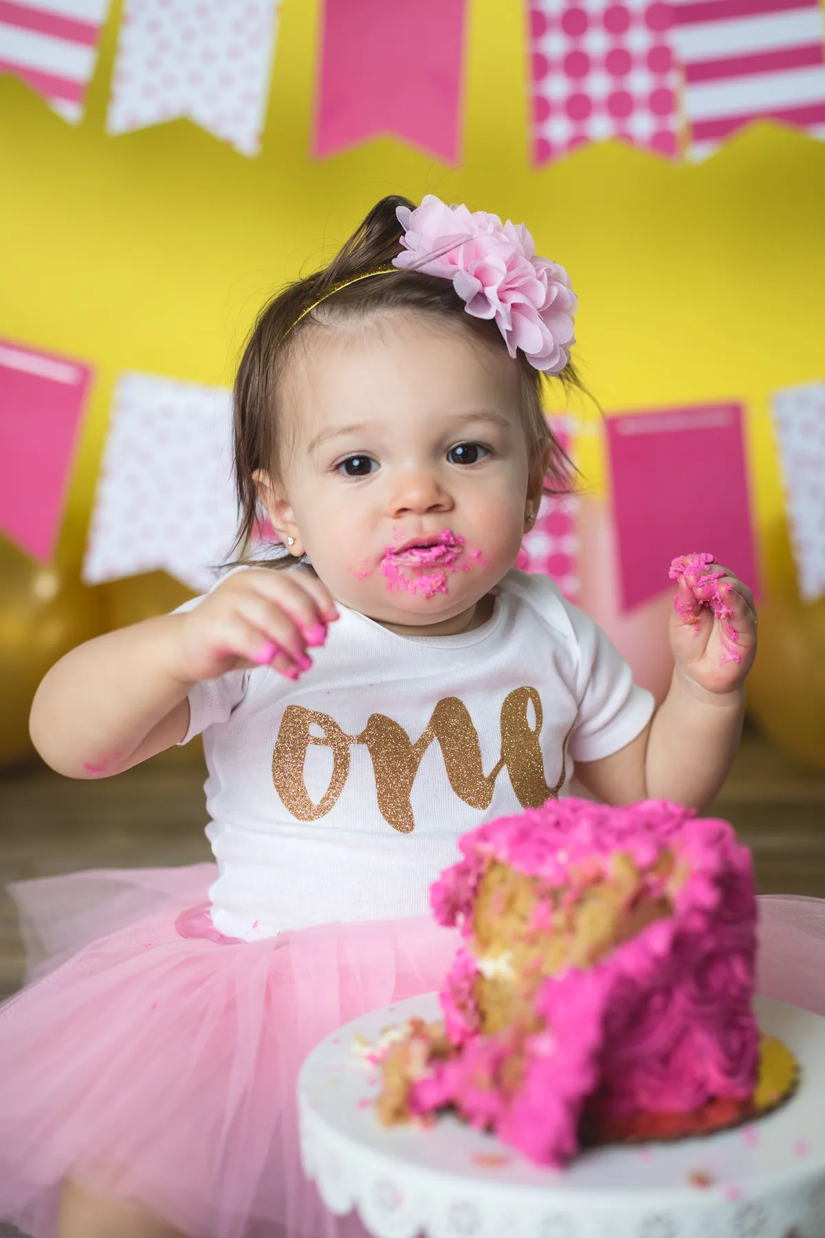 Baby smashing a hot pink cake during a celebratory first birthday photo session in Chicago