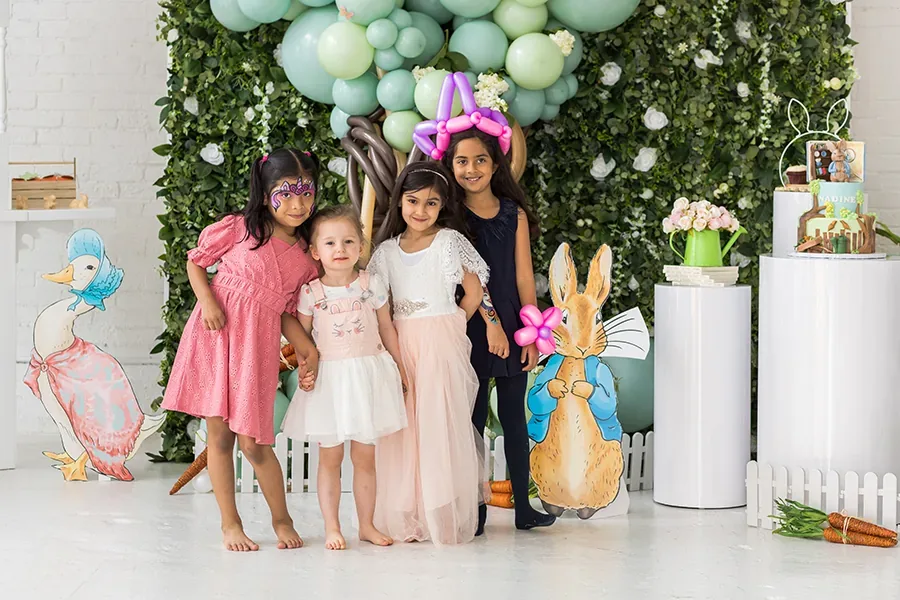 Close-up of baby reaching for a green smash cake with balloons and banner in the background