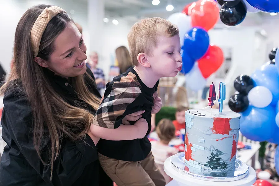 Baby sitting in a styled studio setup with coordinated balloons, crate, and banner for a cake smash session