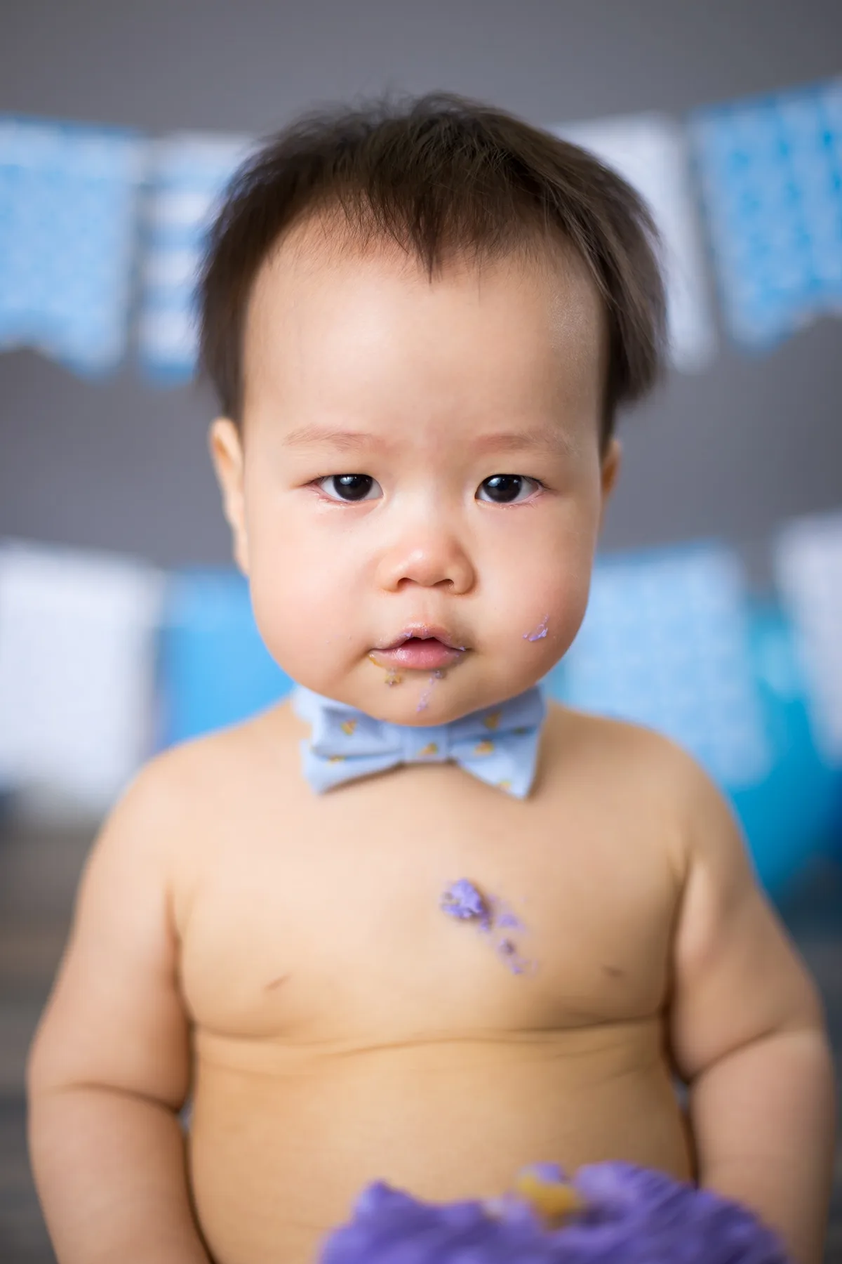 Baby in a purple cake smash setup with coordinated balloons and decorations at a Chicago photography studio
