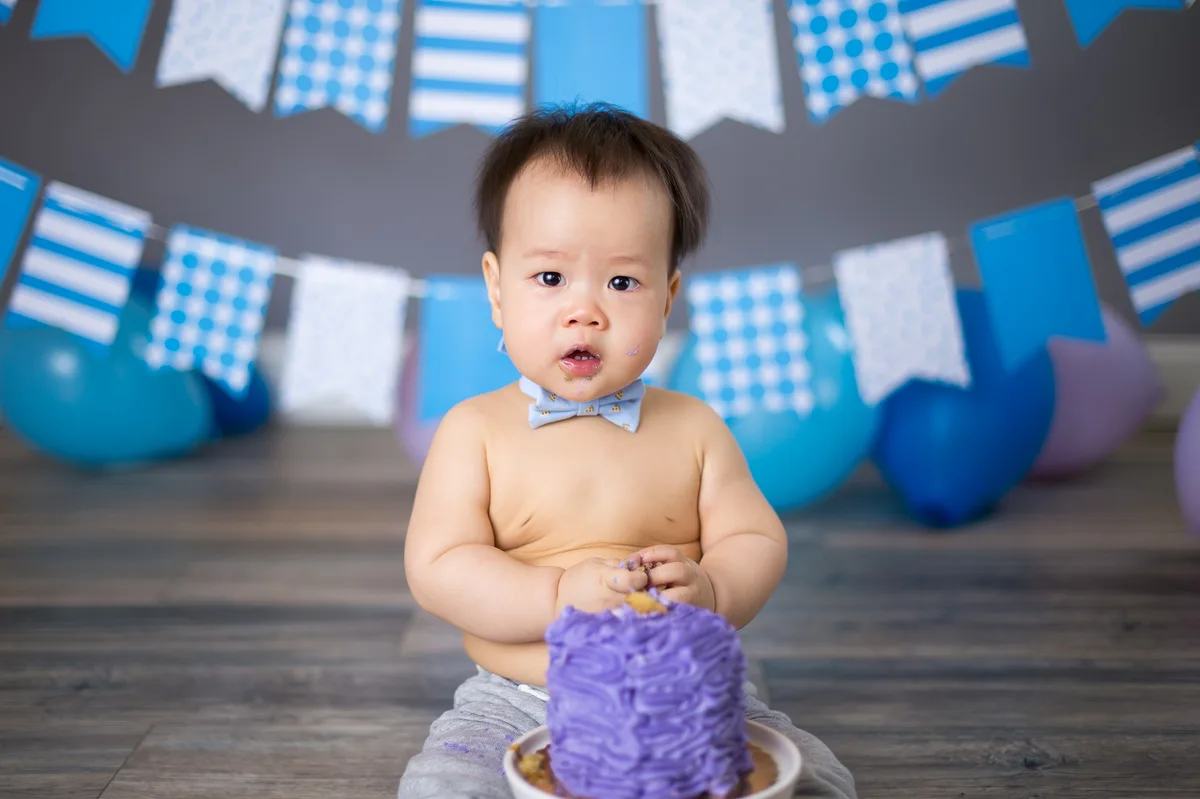 Baby smashing a purple cake during a celebratory first birthday photo session in Chicago
