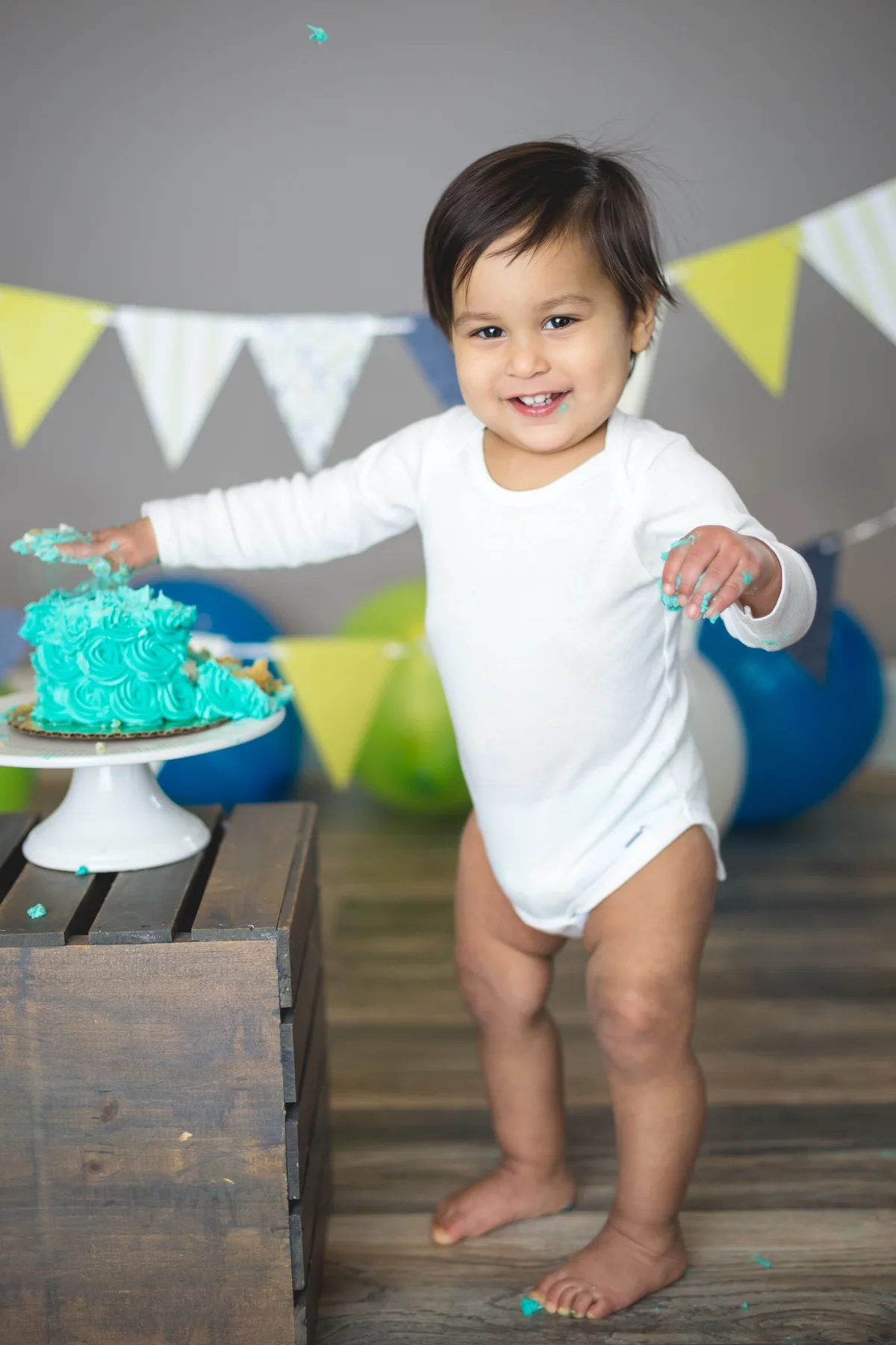 Baby in a styled teal and mint cake smash setup with coordinated decorations at a Chicago photography studio