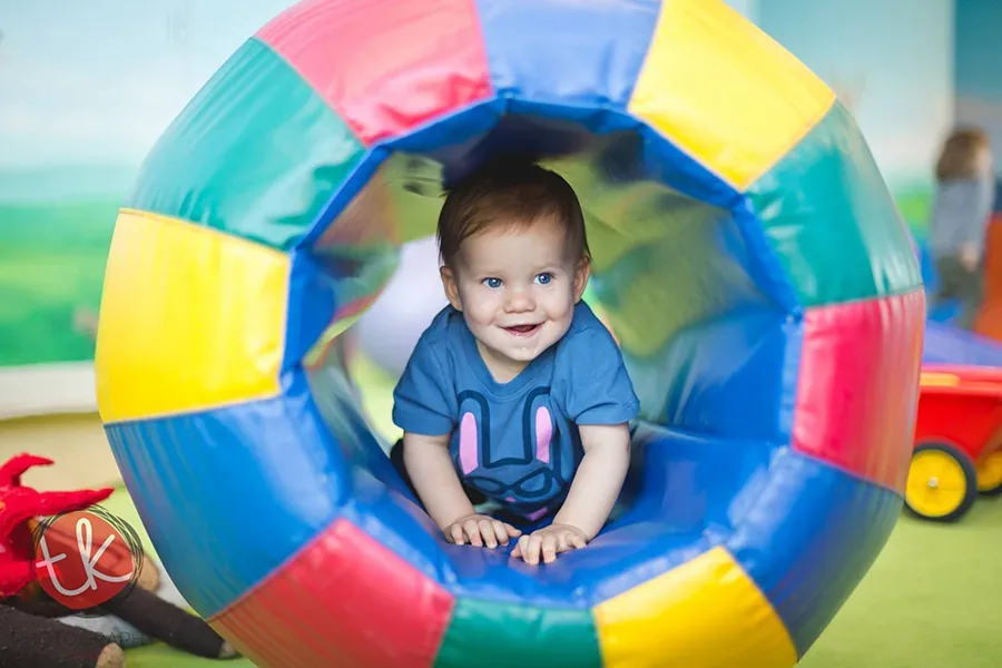 Baby surrounded by colorful balloons during a joyful cake smash portrait session in the studio