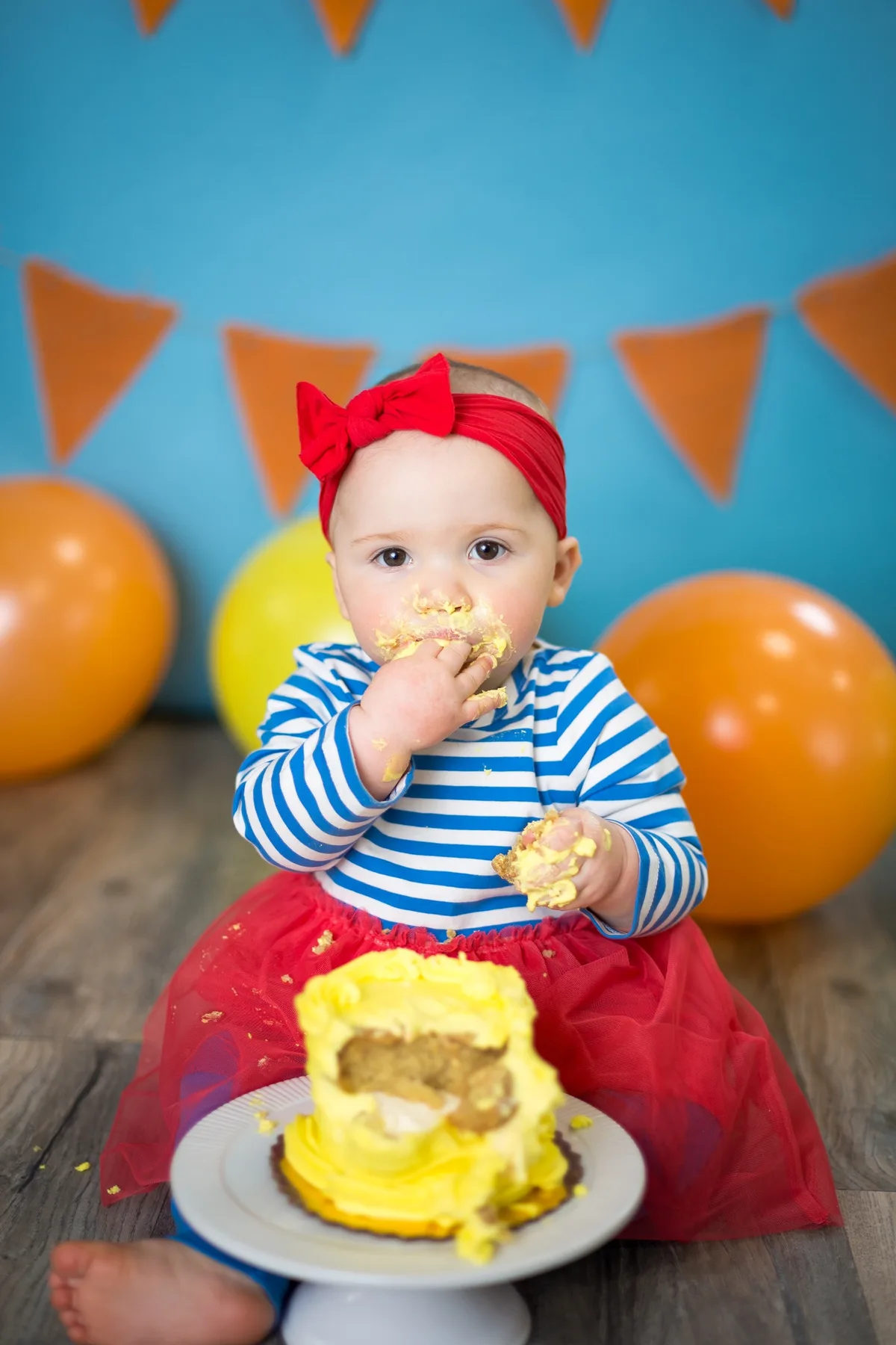 Baby in a yellow cake smash setup with coordinated balloons and birthday decorations at a Chicago photography studio