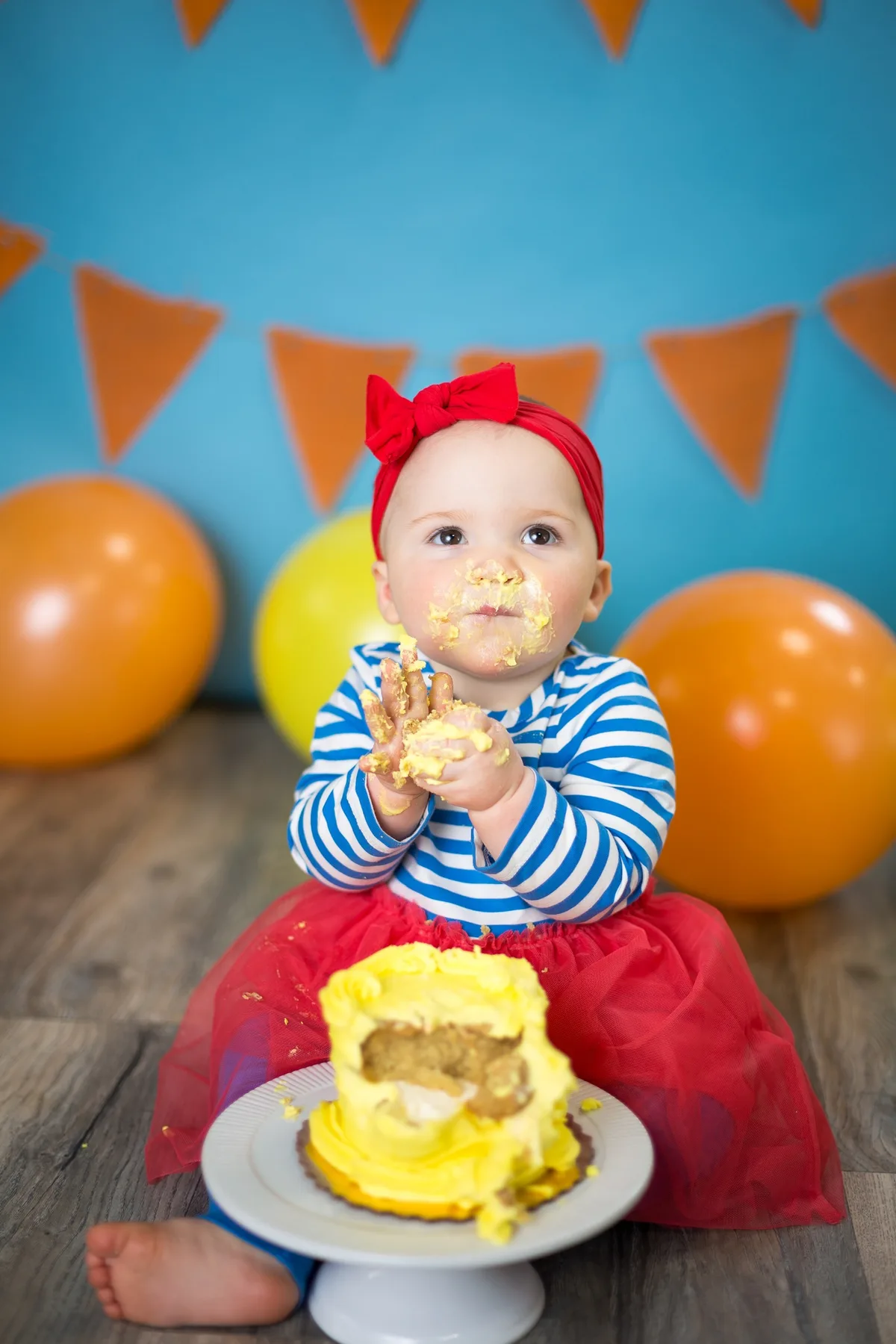 Baby playing with yellow cake frosting during a joyful first birthday cake smash photo session in Chicago