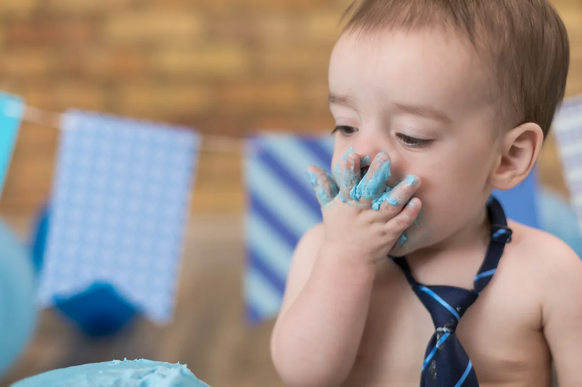 Baby boy reaching for light blue cake during studio cake smash session