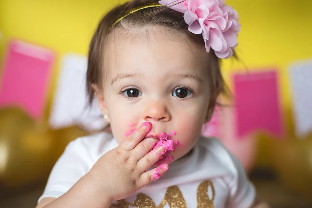 Baby playing with pink smash cake and pink balloons in studio