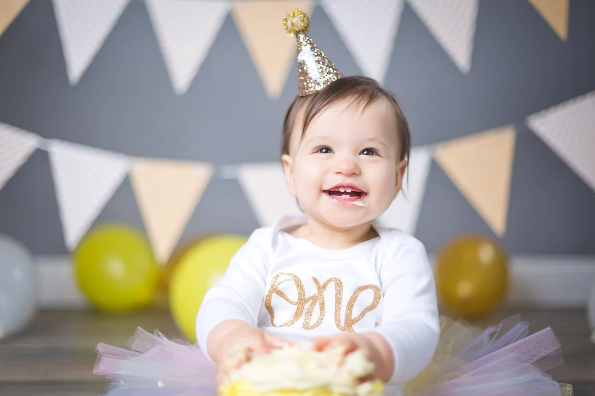 Happy baby with yellow birthday cake and golden banner setup