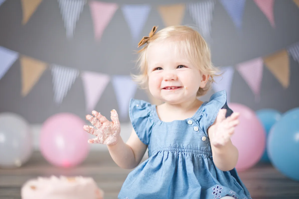 Baby with blush pink cake and coordinated pastel balloon backdrop